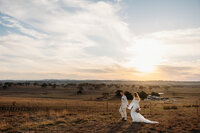 Bride and groom walking across hill during sunset photos on their wedding day at Petrichor Farm