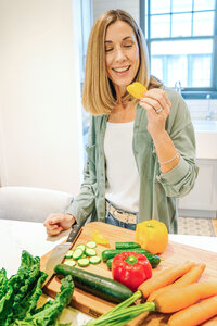 Nutritionist in a kitchen about to bite into a bell pepper with vegetable on a cutting board