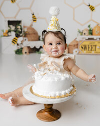 Adorable little one enjoying her bee-themed cake smash, surrounded by honeycombs, frosting, and birthday giggles. Captured by Yucaipa cake smash photographer Kaitlyn Dawn Photography