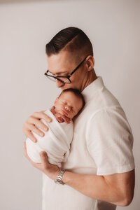 Newborn Photographer in Charleston -Father embraces his infant during Newborn Portrait Session in Charleston, SC.