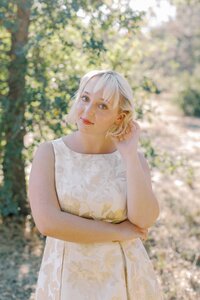 senior girl with one arm crossed, one tucking hair behind her ear during her senior photo session on Stanford campus