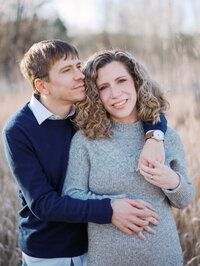 A couple embracing and holding the woman's pregnant belly at Magnuson Park