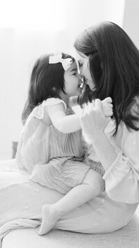 Black and white close up photo of a mother holding her little girl as they pose for an in studio session.