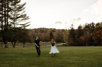 Couple dancing together in a field with the woman wearing a long flowy skirt during a New England engagement photoshoot, capturing romantic and joyful outdoor moments.