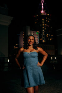 Senior portrait in downtown Mobile, Alabama — waist-up with the glowing city skyline in the
background.