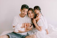 toddler giving mom a hug, dad holding newborn baby boy