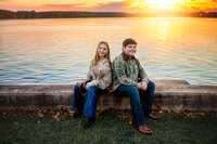 Two older siblings sitting by the water at sunset during a New Bern portrait session