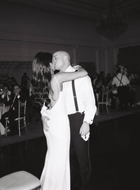 Couple in wedding attire kiss during their first dance