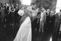 Bride and groom sharing a first dance at wedding reception with guests watching