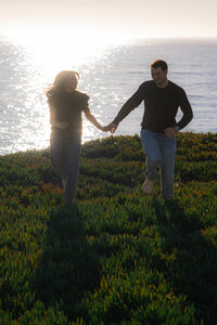 couple running on cliffside in santa cruz california
