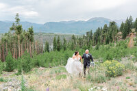 A bride and groom walk up a hill near Sapphire Point with mountains in the background photographed by Jackelynn Noel Photography.