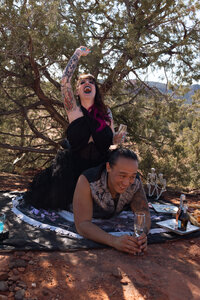 Bride relaxing on a picnic blanket with champagne during her Sedona elopement