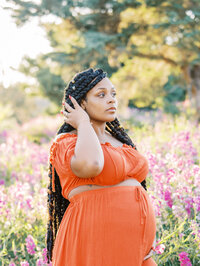 Pregnant woman looking in the distance and brushing her hair back