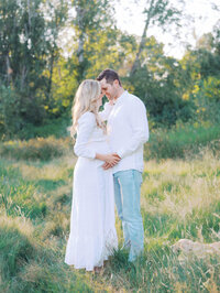 Husband and pregnant wife standing close together and holding hands