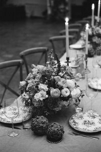 Centre de table floral abondant aux tons pastel, chandeliers et vaisselle fleurie, chaises en X en arrière-plan, décor de réception au Cathcart, Montréal