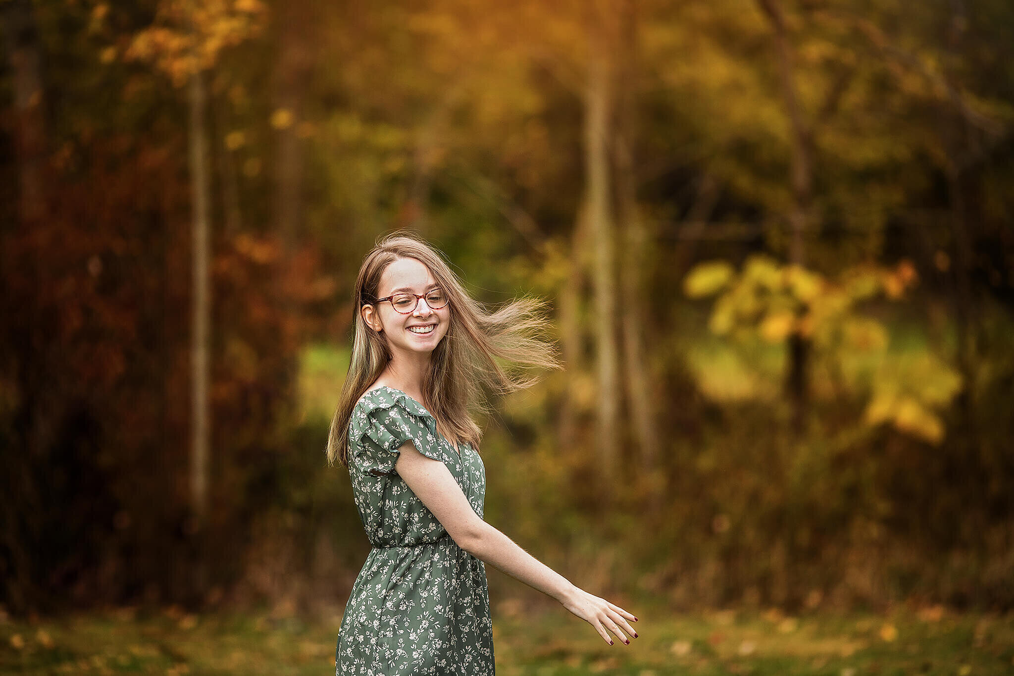 marion ohio high school senior twirling in front of the woods wearing a green and white dress