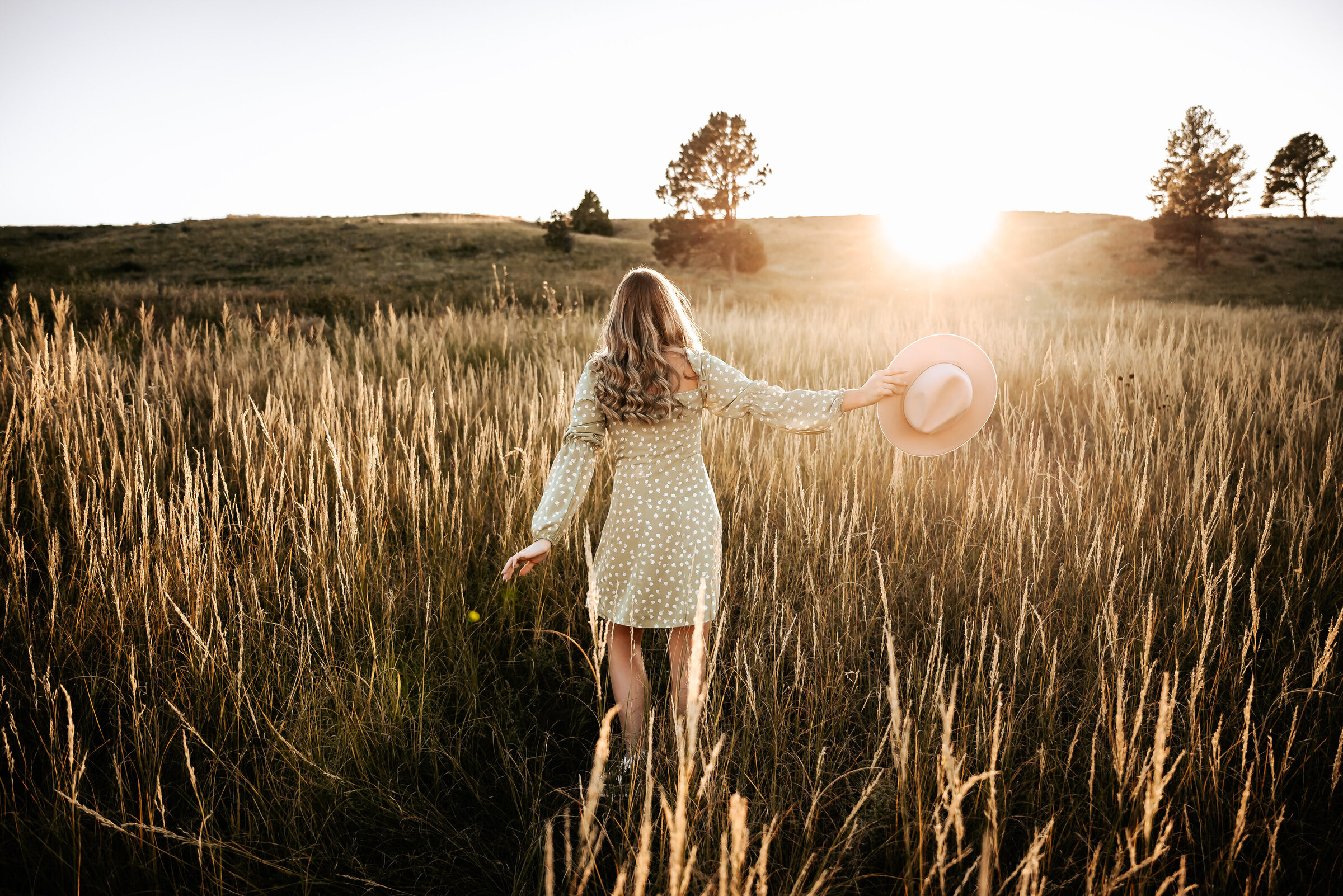 Girl dances in field near Lake McConaughy while holding hat