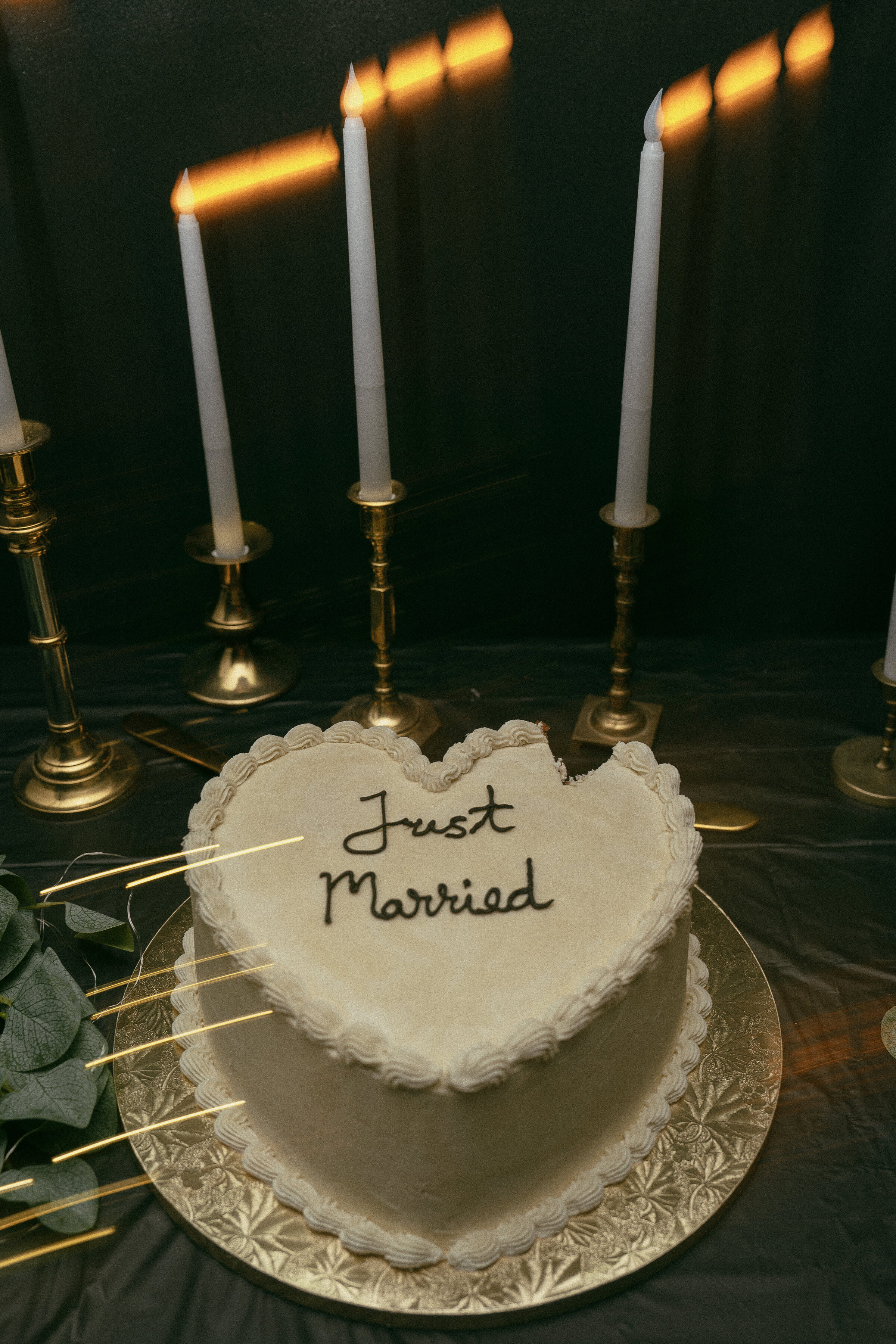 Wedding cake with "Just Married" on top and candles in the background.