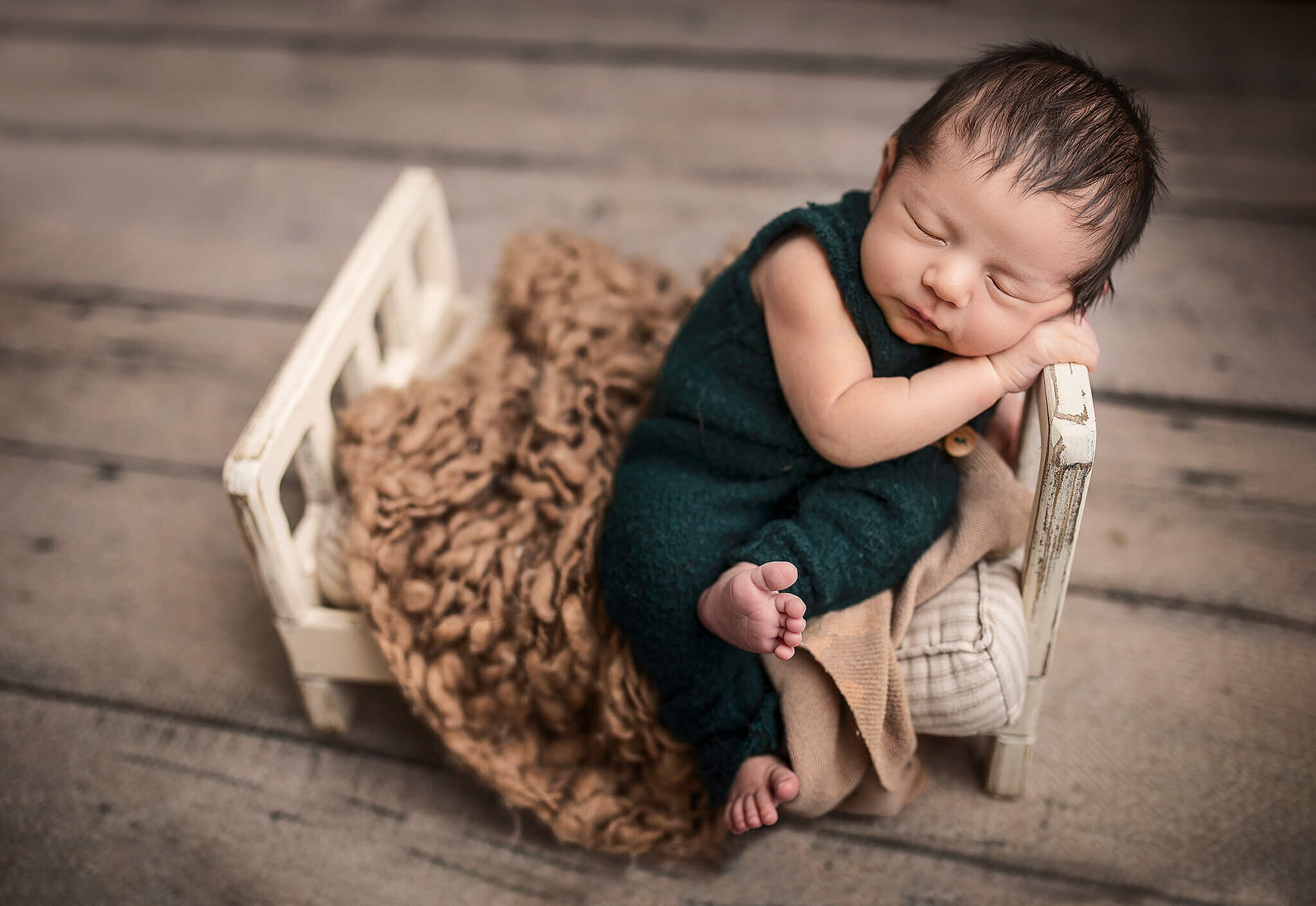 newborn baby boy sitting up in little bed sleeping on side of the bed bucyrus ohio studio