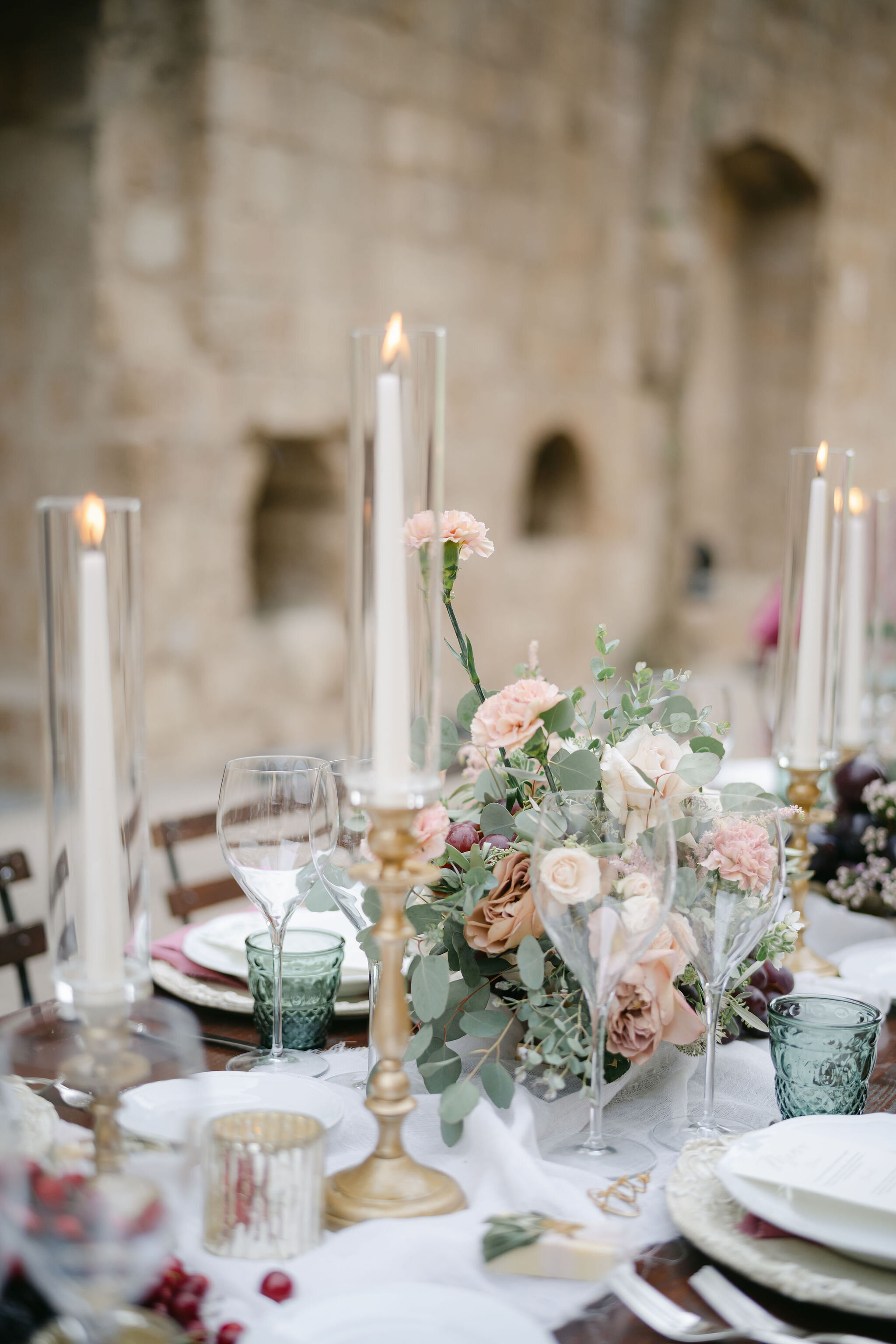 Blush and rust coloured wedding table flowers and gold tapered candles at a wedding at La Badia di Orvieto