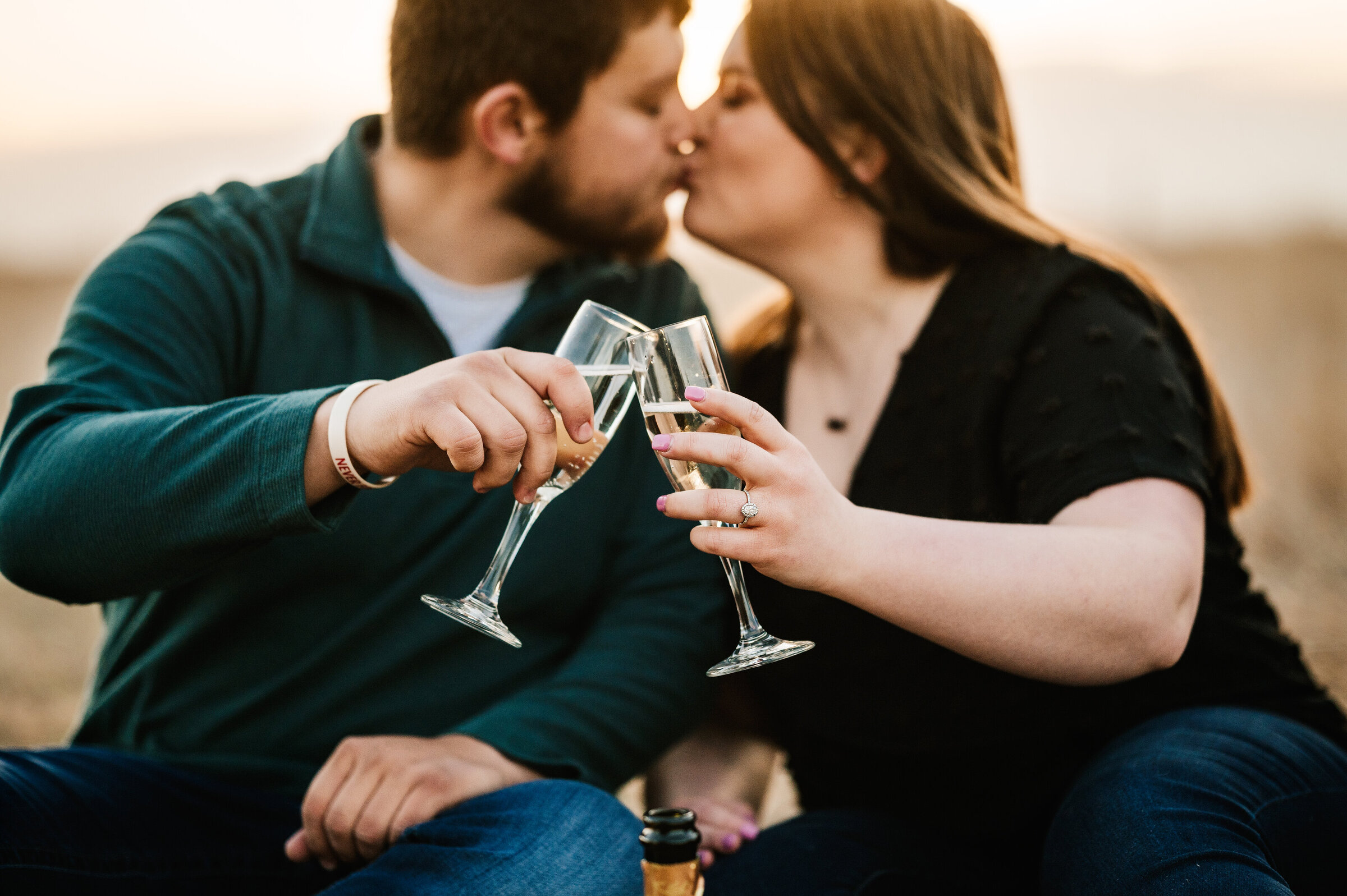 Couple clinks champagne glasses while kissing