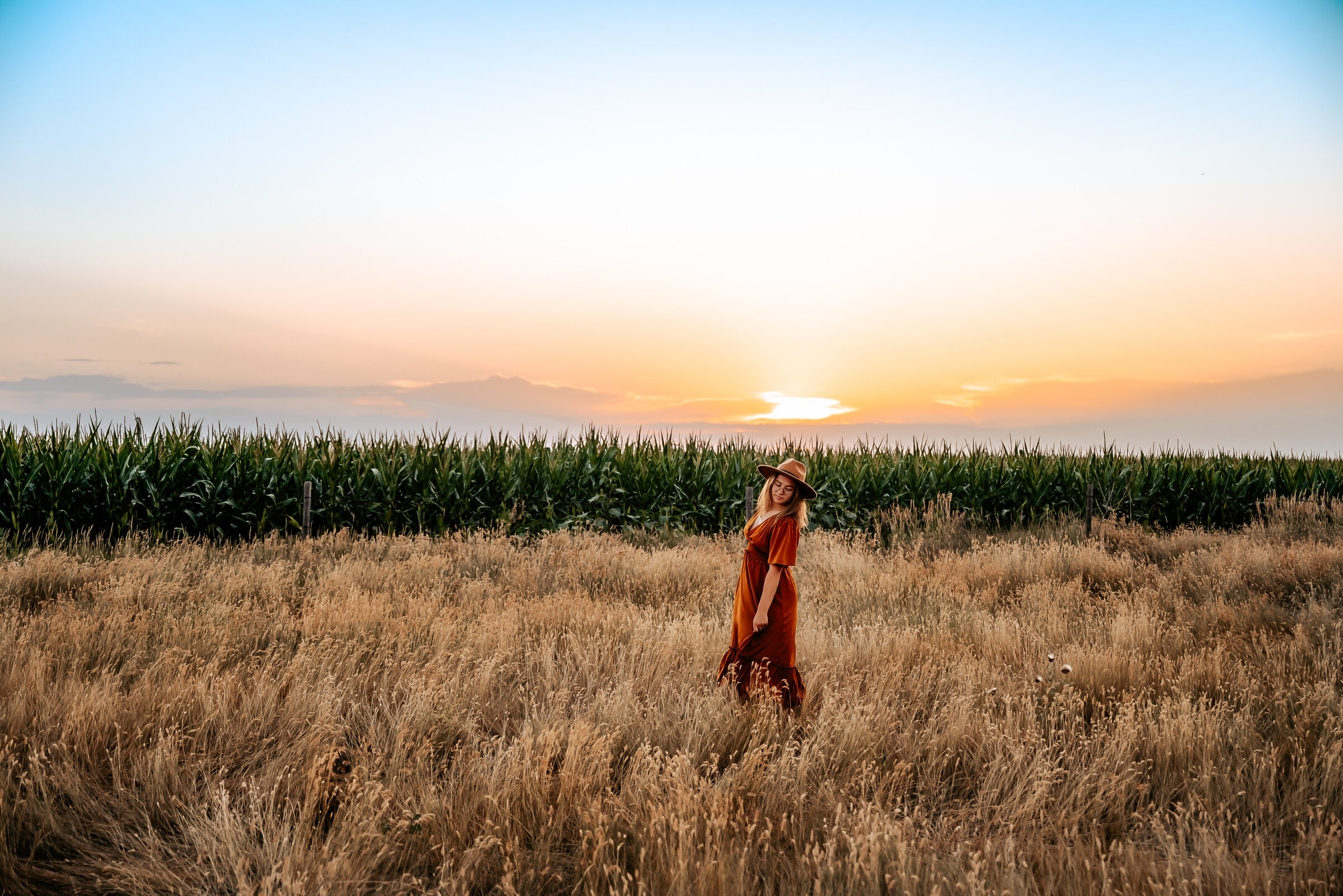 Girl walks through field in long grass with boho outfit