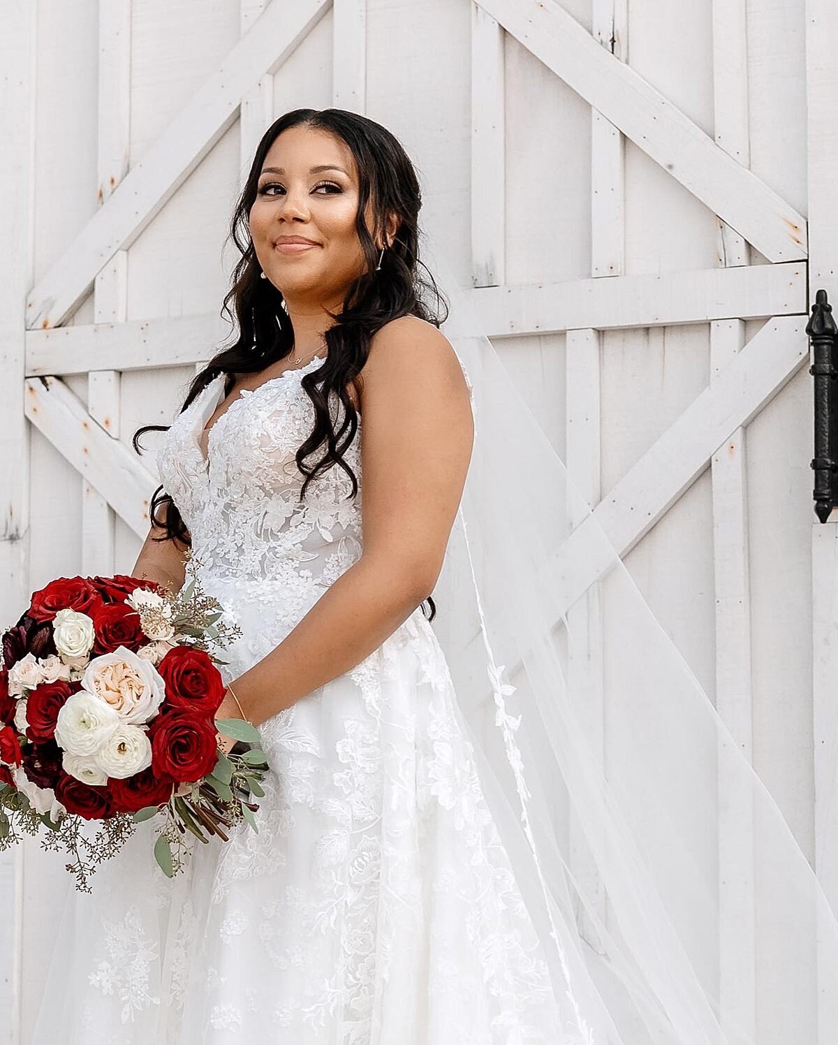 Bride outside of White Dove Barn holding rose filled bouquet