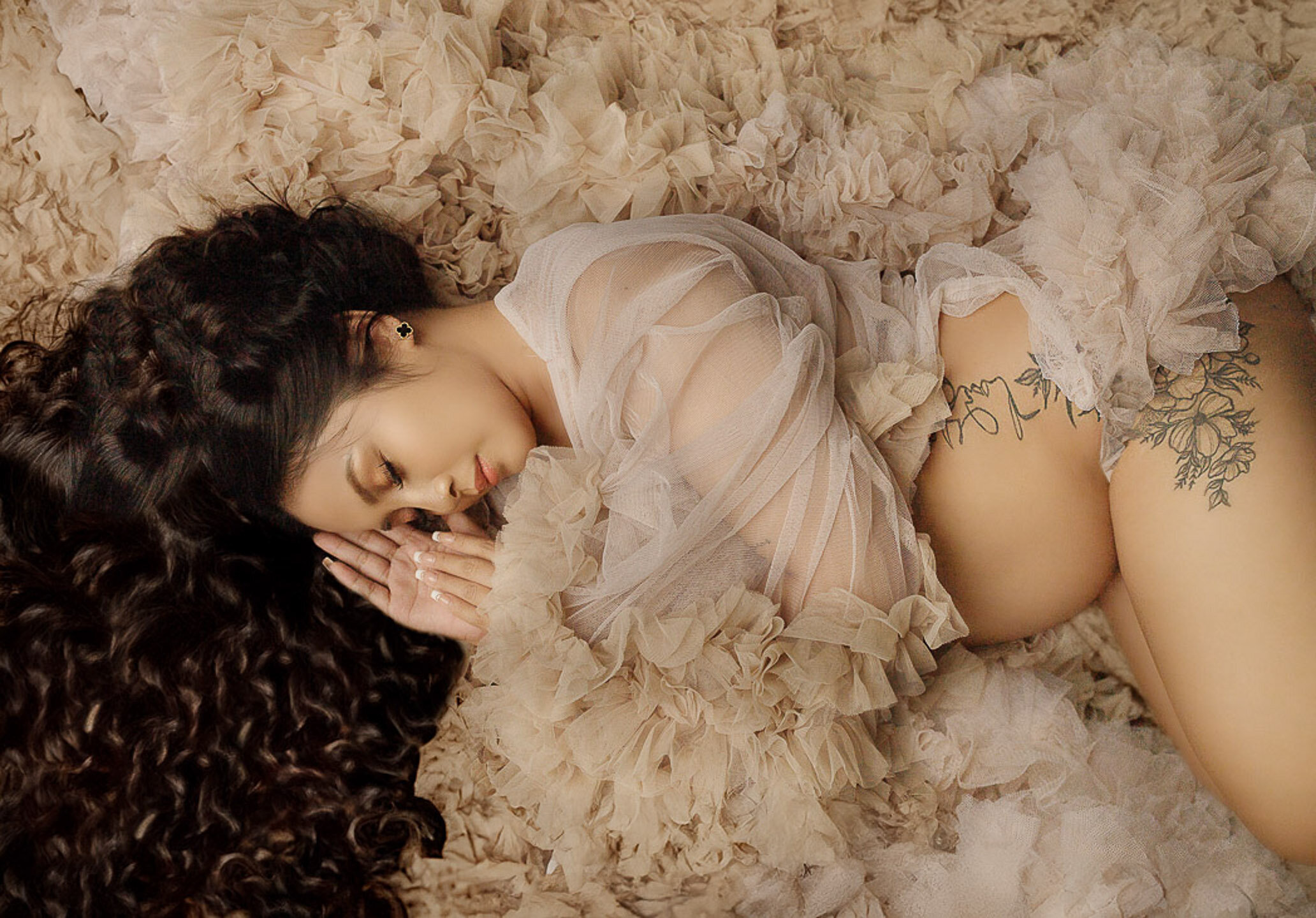 pregnant sleeping wearing beige maternity gown showing her leg tattoo