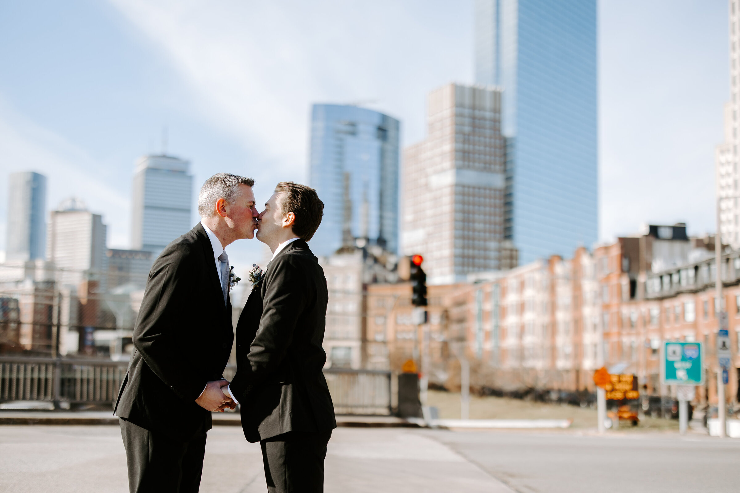 Groom and groom kiss infront of the skyline in Boston Massachusetts