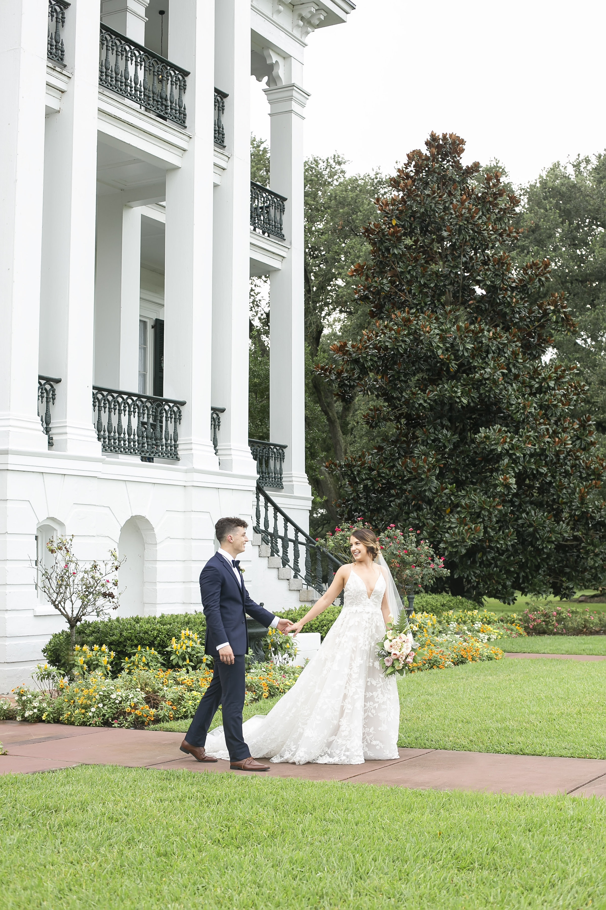 Bride and groom walking in front of Nottoway Plantation in Louisiana