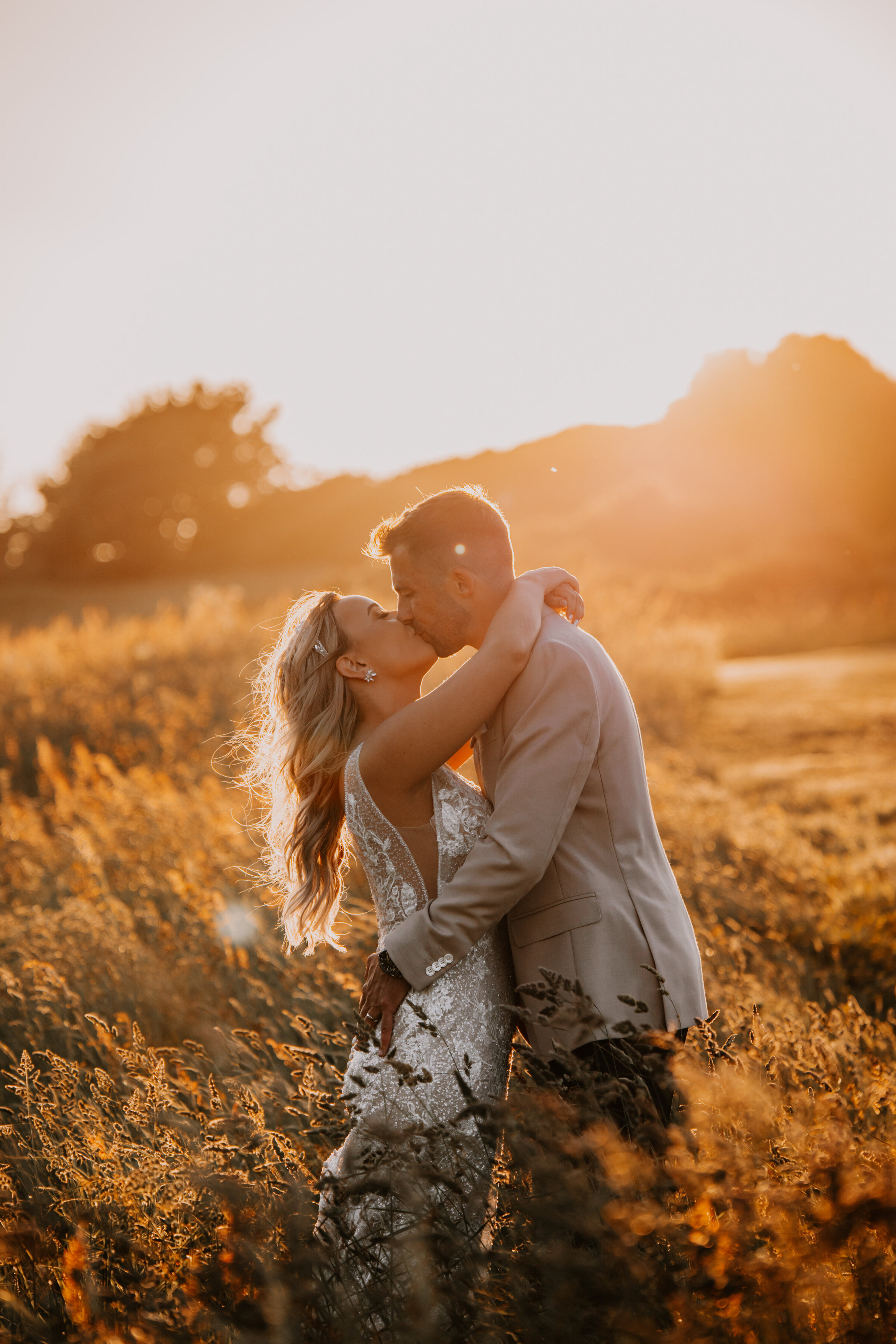 couple embracing during sunset in field