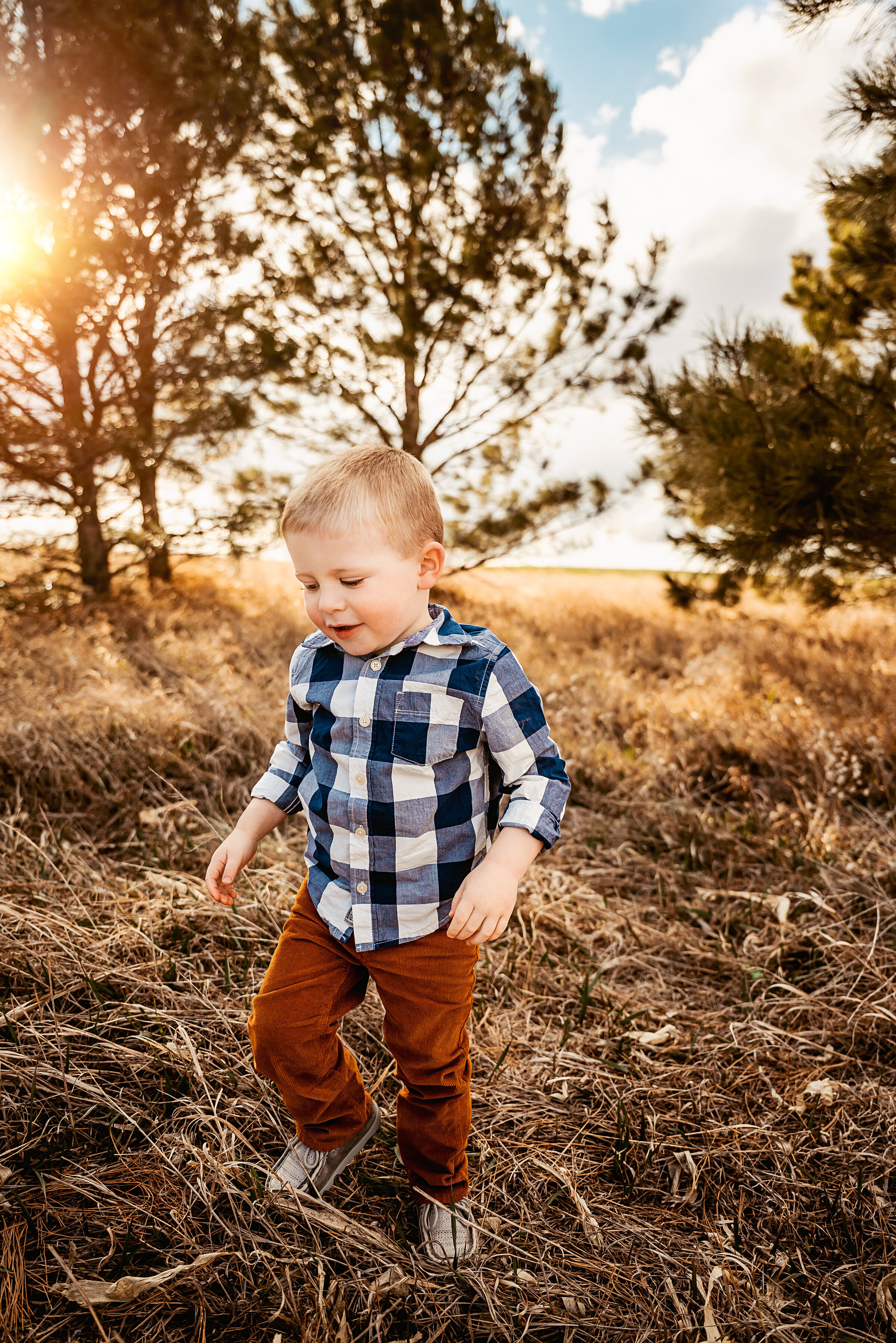 Little boy runs through field while sun shines