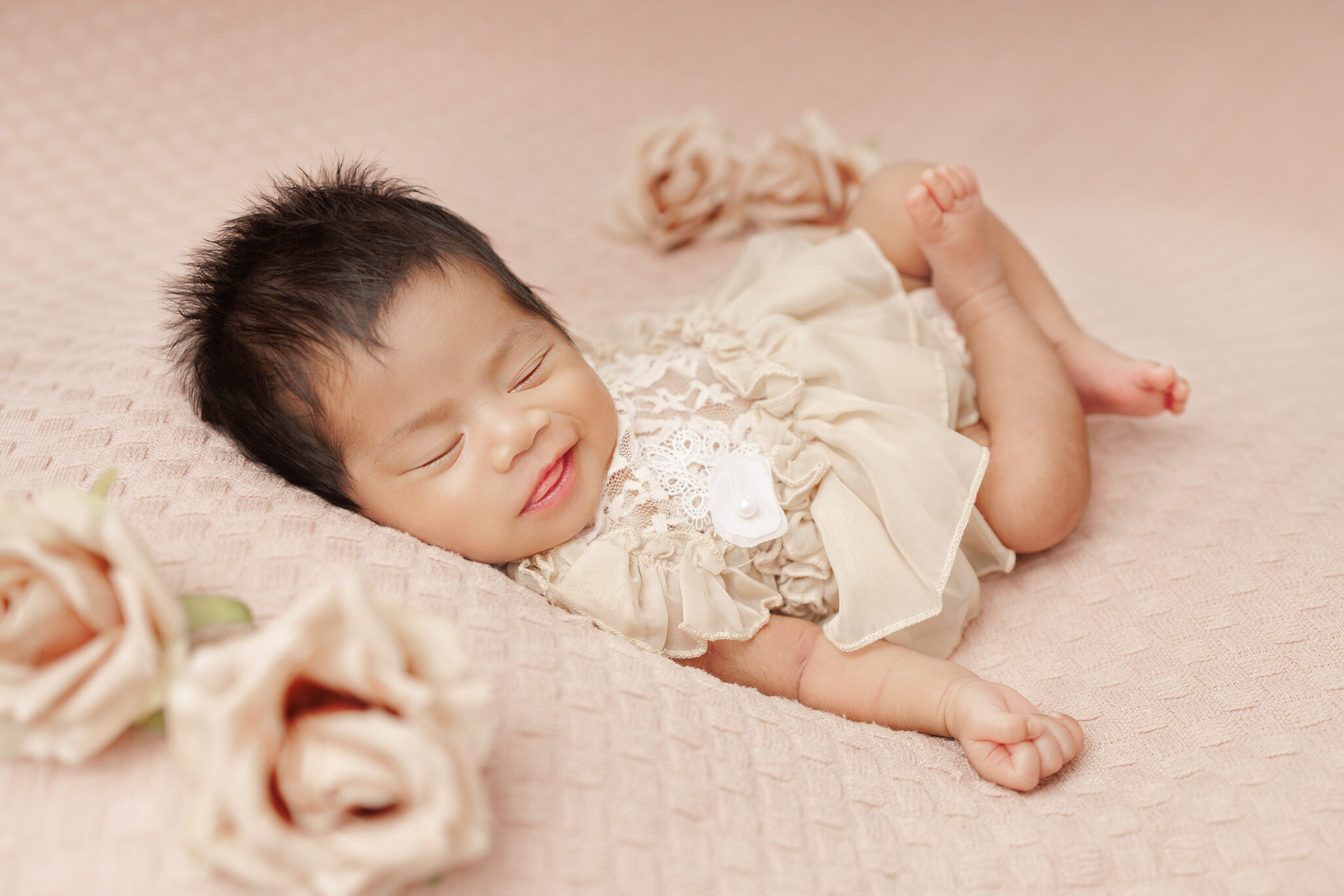 baby girl wearing beige outfit smiling while asleep