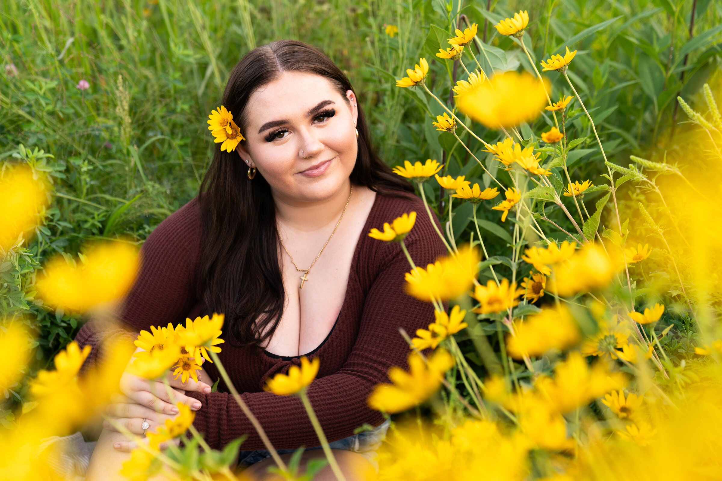 Girl sits in a wildflower field for her senior pictures