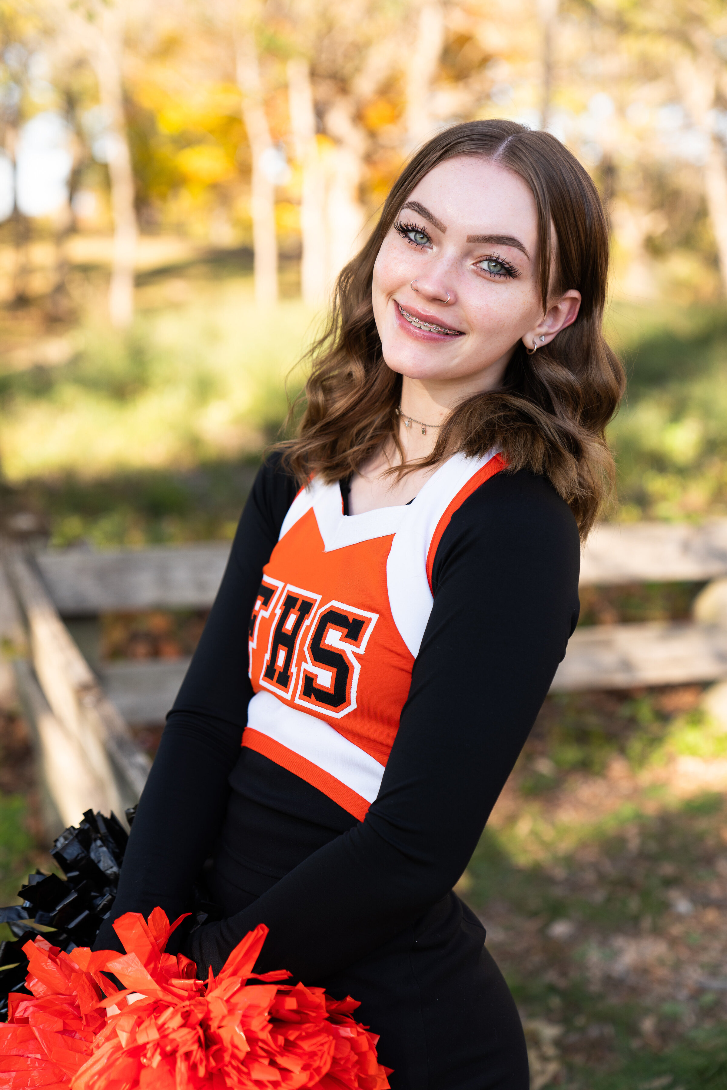 High school girl wearing her cheerleader outfit poses for her senior photos.