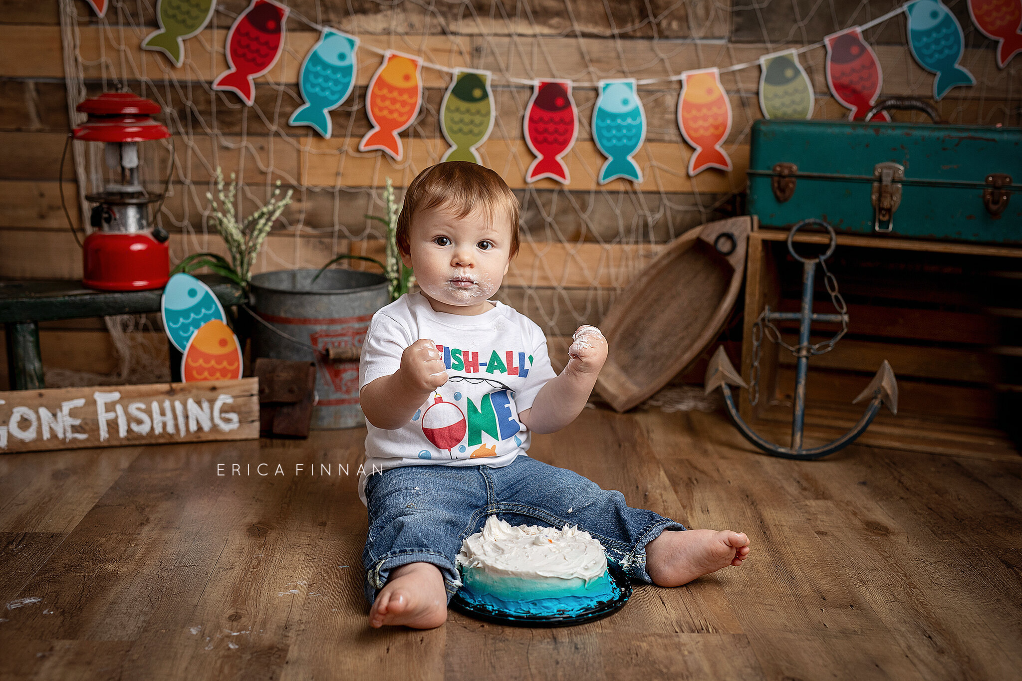 Baby boy sitting with cake  in front of gone fishing cake smash background