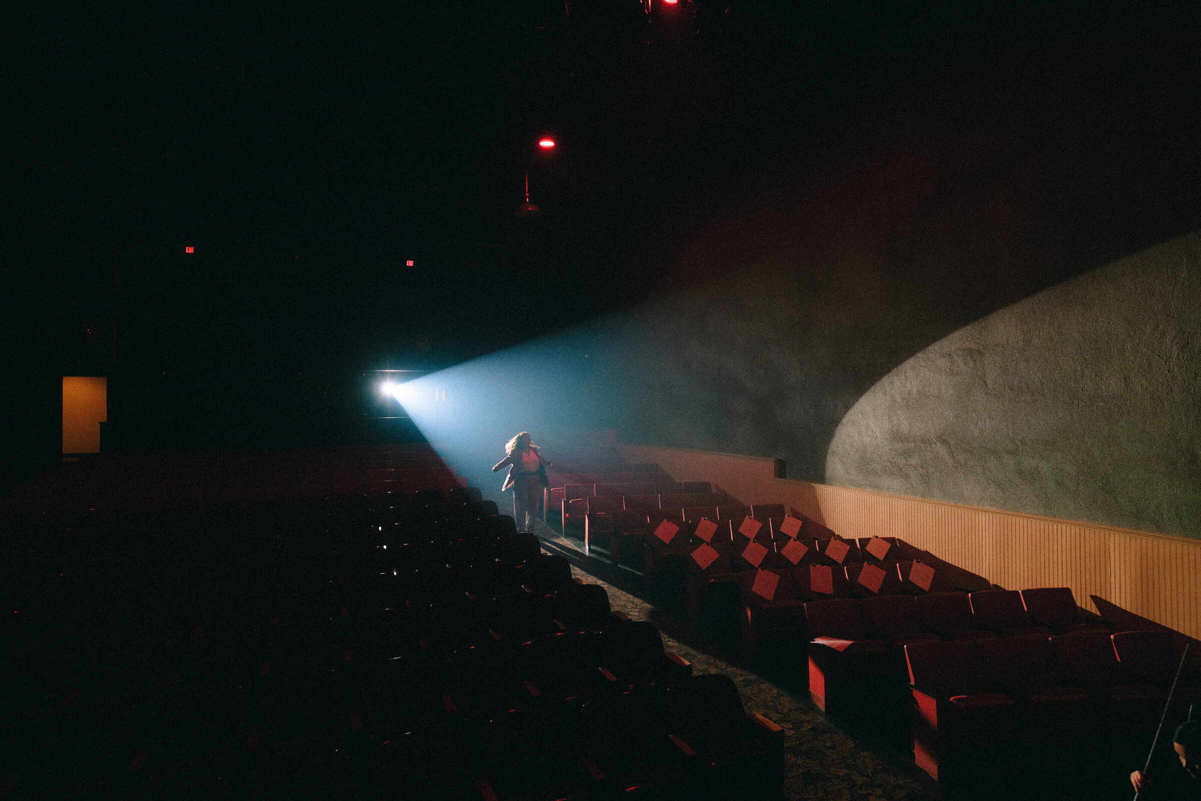 theater spotlight aisle scene creative brand imagery person walking in theater aisle with stage spotlight shining across the space