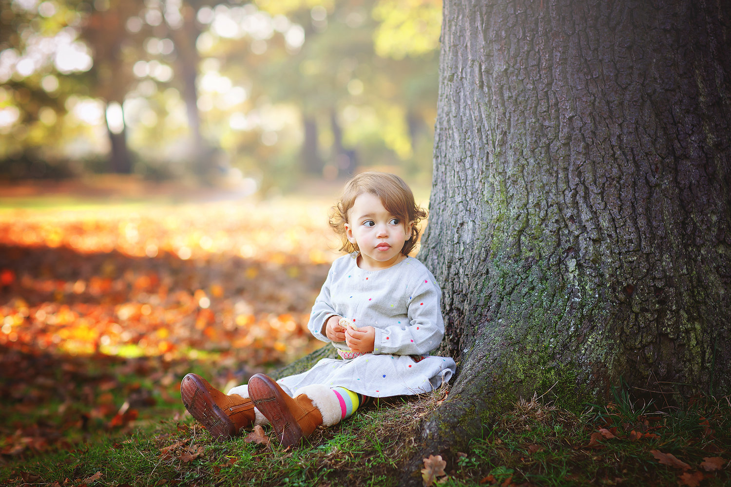 little girl sitting under tree