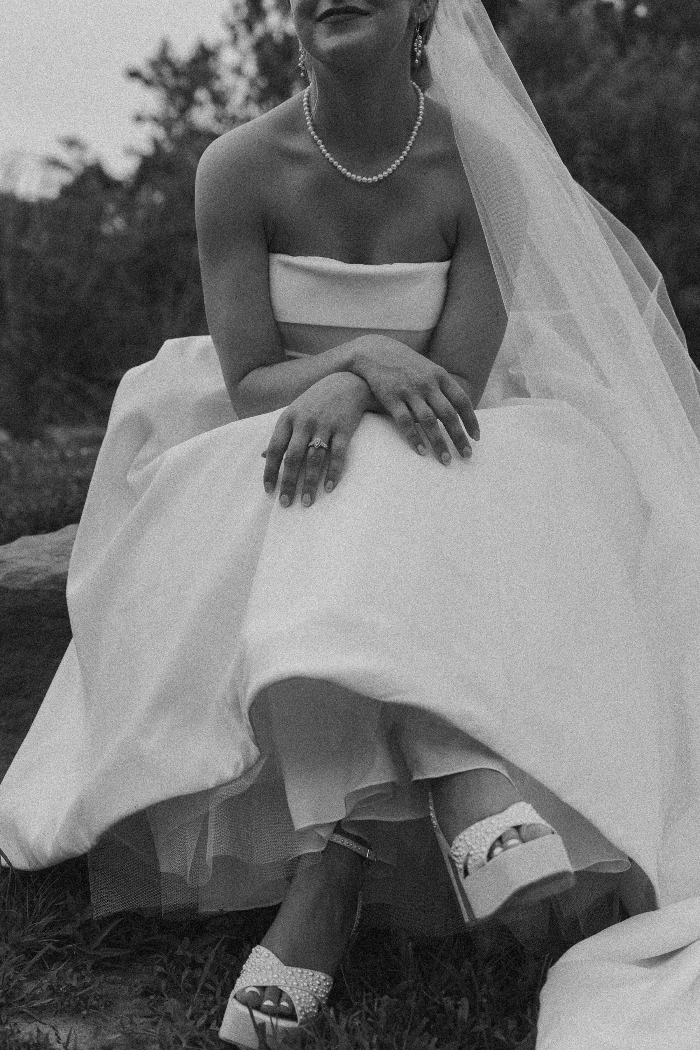 Black and white photo of a bride sitting down showing her shoes.