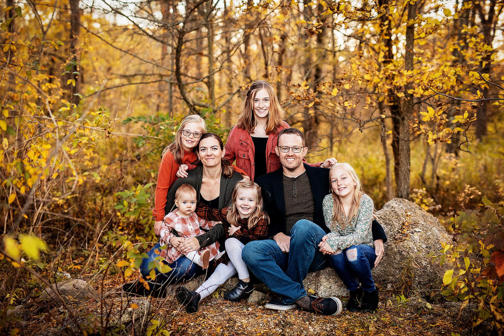 Family of seven sitting on rock in the fall