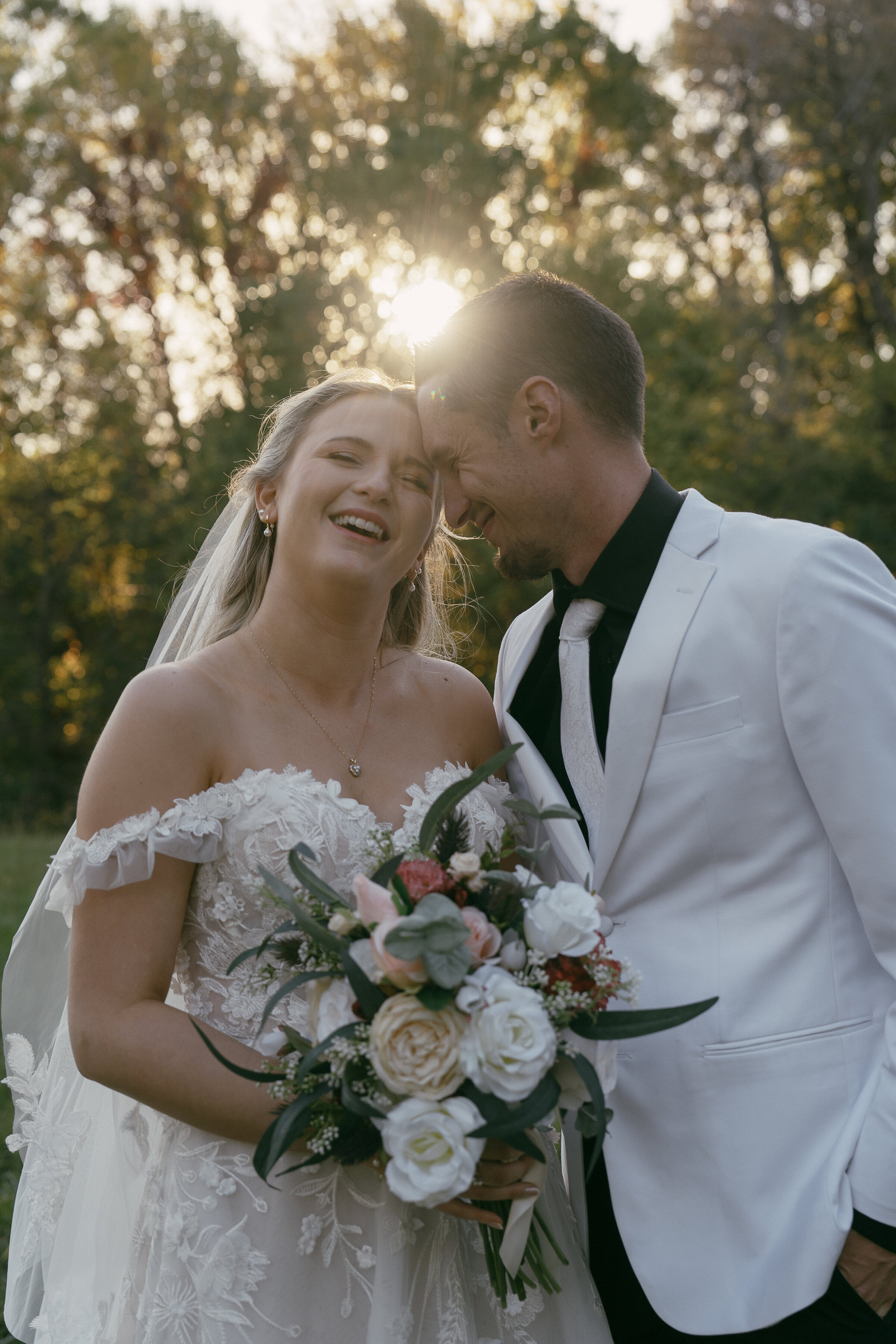 Joyful bride and groom with a bouquet in sunlight.