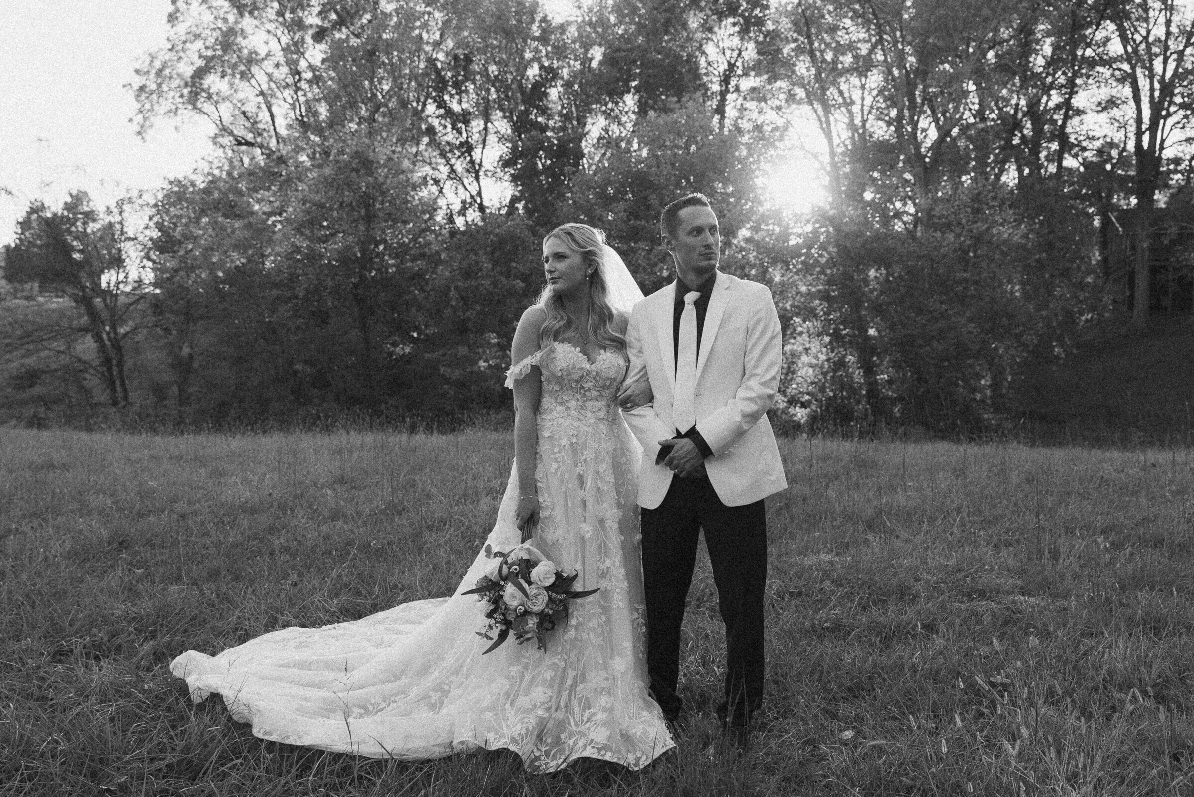 Black and white portrait of bride and groom in a field.