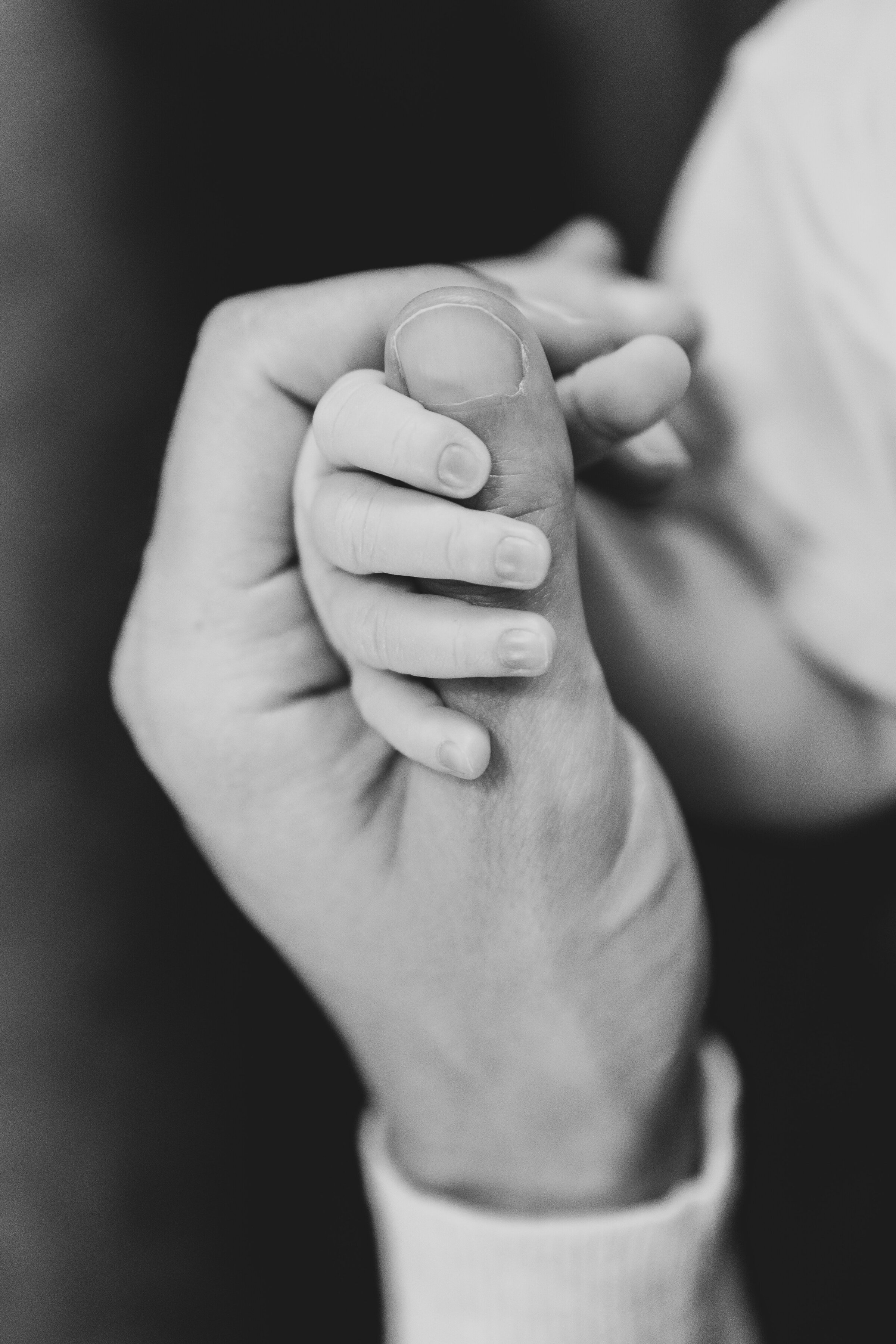 Newborn baby wrapping their finger around their dad's thumb