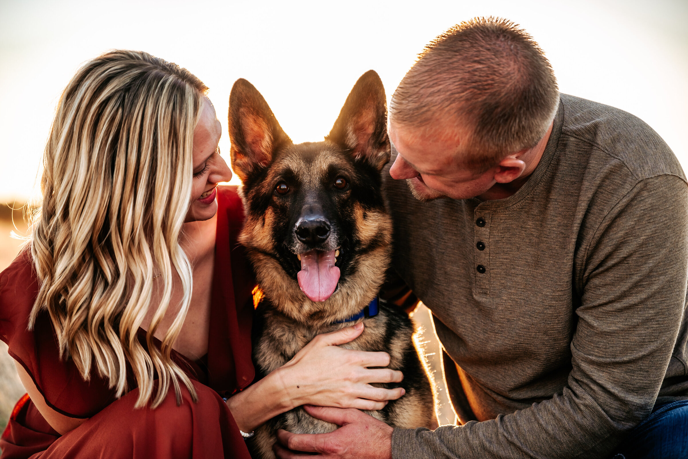 Couple loves on german Shepard dog while dog smiles