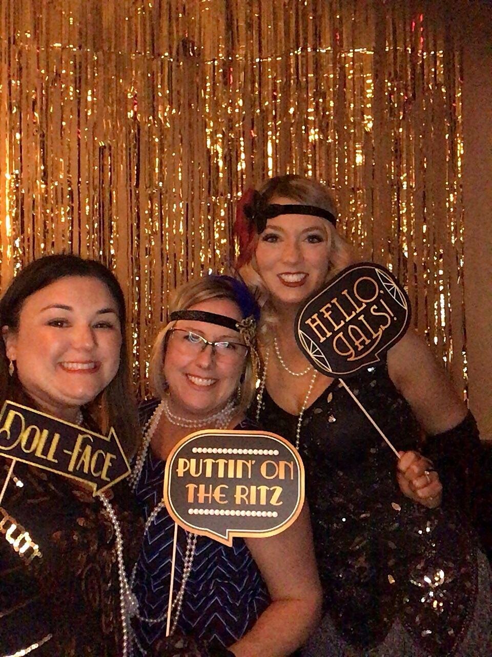 Roaring 20's themed party with guests in flapper dresses posing in photobooth