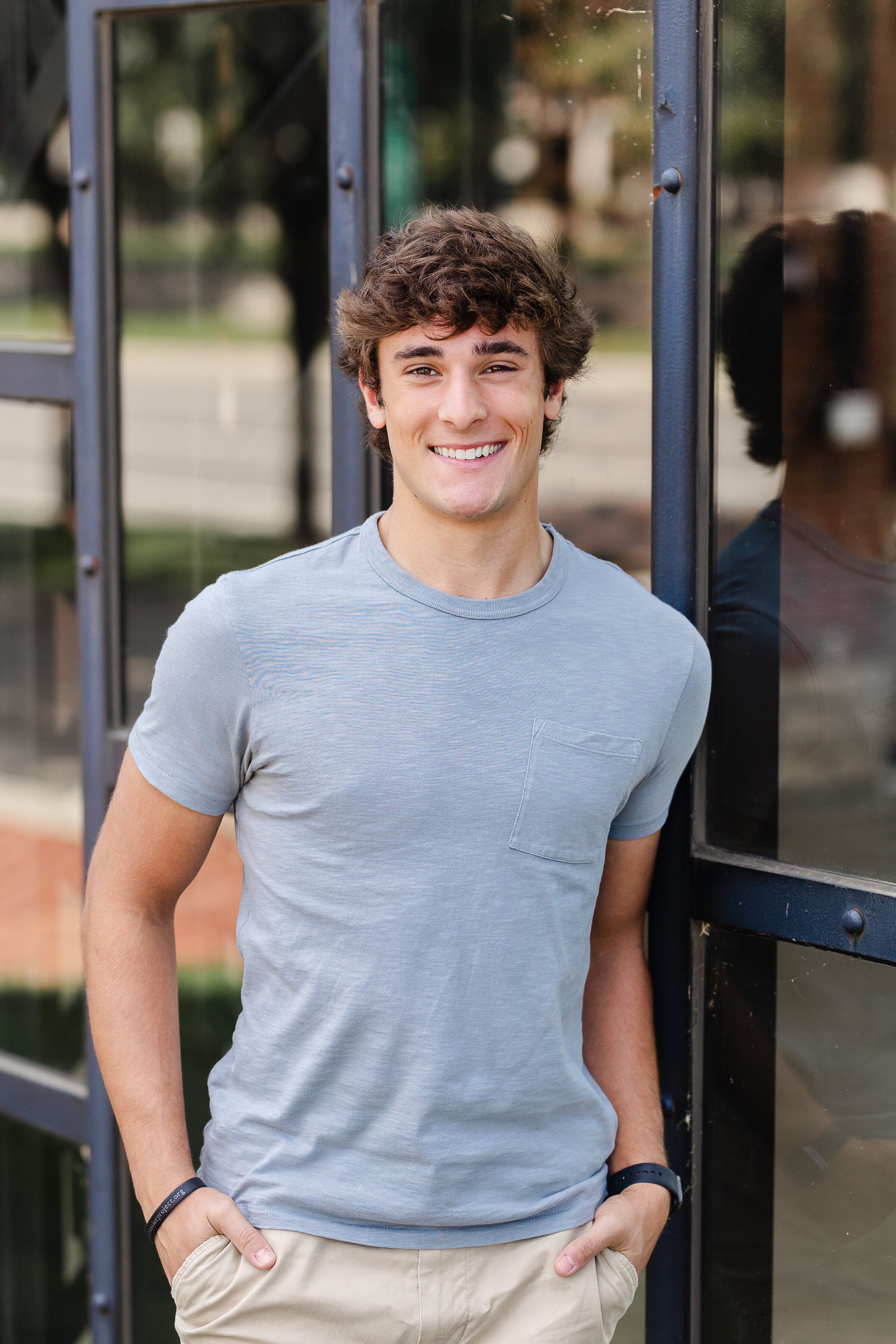 senior guy standing against windows at North Bank Park for his senior photos