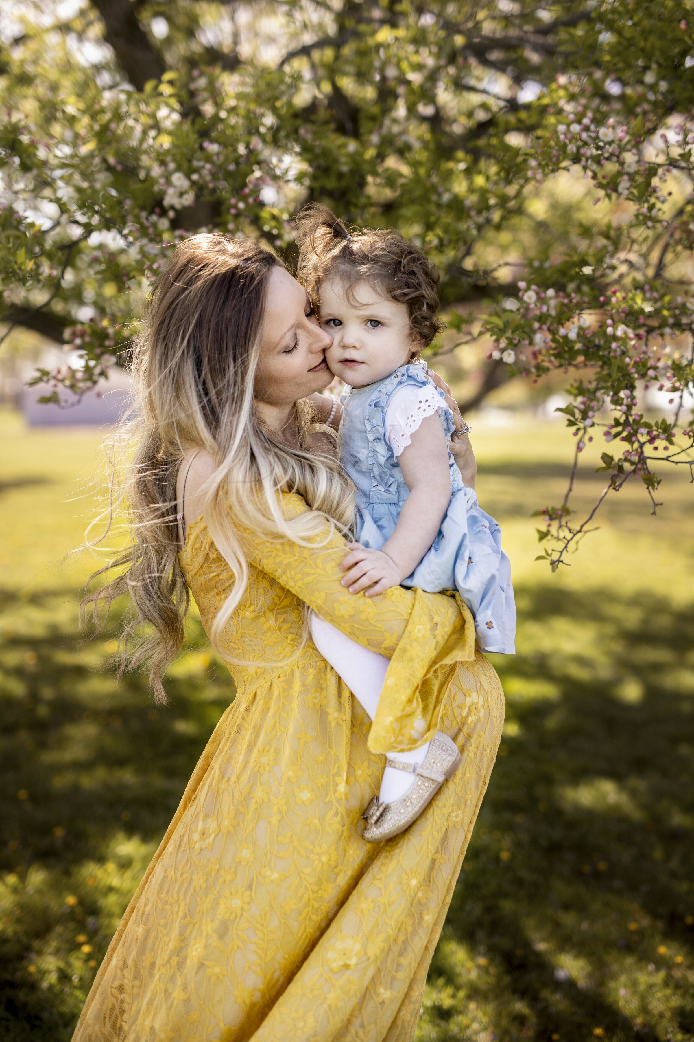 Mother holding on toddler over her pregnant belly in a beautiful yellow gown in Columbus Ohio