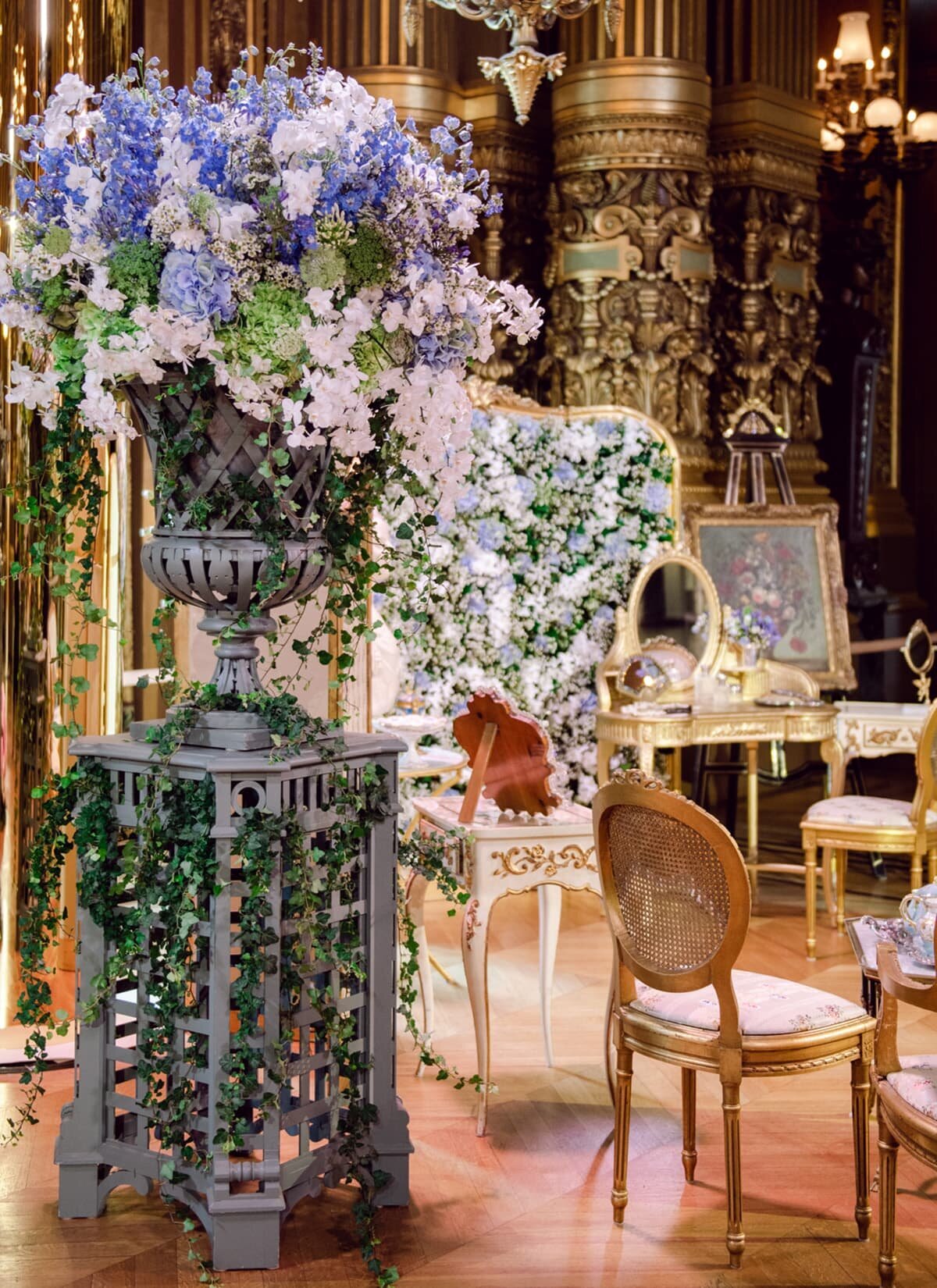 Large vase of purple flowers in ornately decorated room with gold