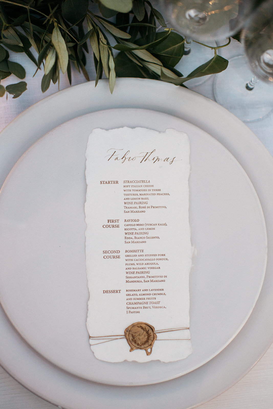 A handmade paper wedding menu on a bespoke ceramic Puglia plate of a wedding at Masseria Moroseta