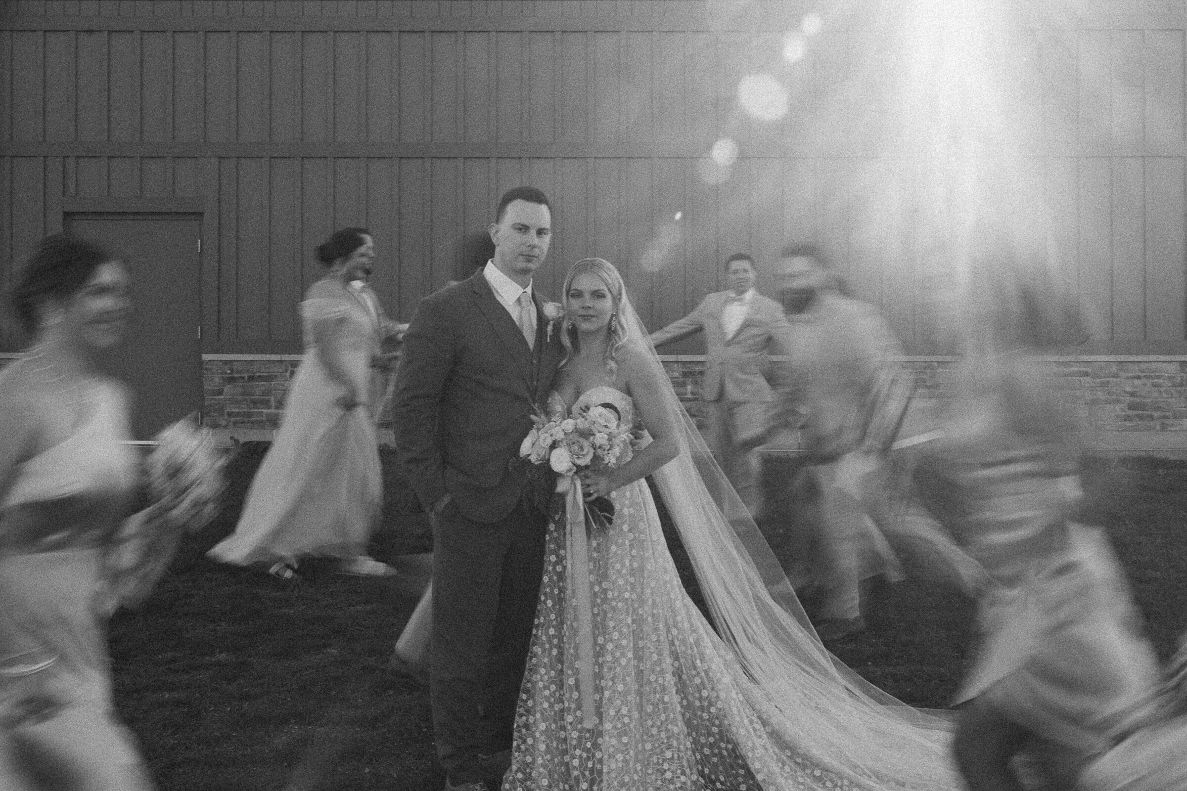 Bride and groom in a blurred motion photo with guests.
